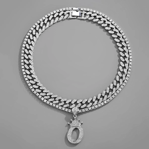 Detail of silver iced-out crown letter O pendant with layered Cuban and tennis chains