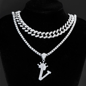 Detailed view of silver iced out Cuban and tennis chain set with crown letter V pendant