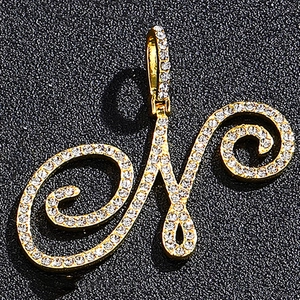 Detail view of iced out golden cursive letter M pendant with sparkling zircon stones