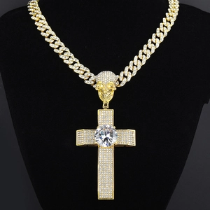 Detail of luxury gold Cuban chain necklace with iced-out cross and skull pendant