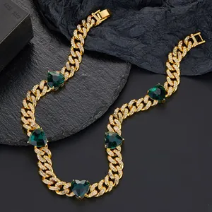 Detail of gold Cuban chain necklace with iced-out crystals and emerald green heart stones