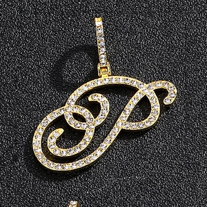 Close-up of golden letter P pendant with sparkling clear zircons on black leather