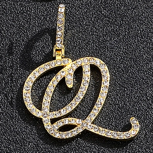 Macro shot of gold-plated cursive letter Q pendant with pavé set cubic zirconia stones
