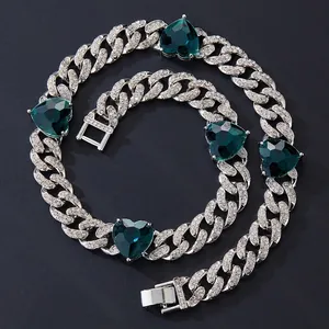 Detailed macro view of silver Cuban chain necklace with emerald green heart shaped gems