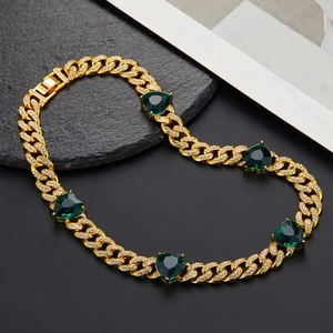Detail of gold Cuban link chain featuring heart-shaped emerald green stones and pavé diamonds