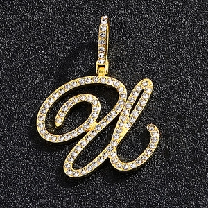 Close-up of golden letter W pendant with iced out white zircons on a dark background