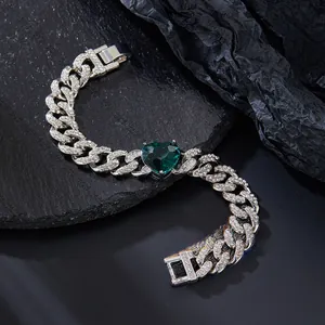 Macro shot of silver Cuban chain necklace with iced-out heart-shaped green gemstone charm