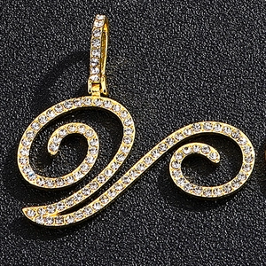 Macro shot of 18K gold cursive letter pendant with pavé set cubic zirconia on leather