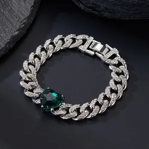 Detail of a Cuban link bracelet with iced-out zircons and a large green heart gem