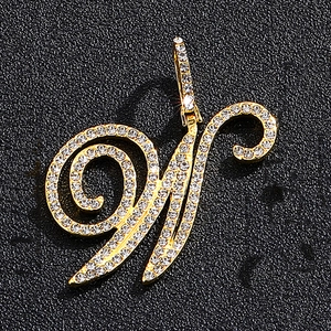 Macro shot of luxury gold-plated letter M pendant with iced-out pavé zircons