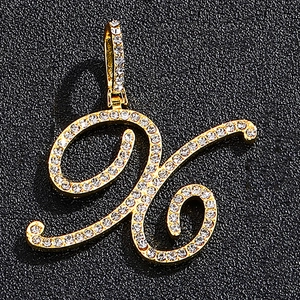 Detailed macro view of a gold-plated cursive letter pendant encrusted with white crystals