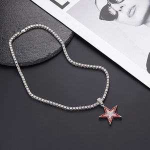 Detalle macro de la cadena tenis plateada y colgante de estrella con circonitas rojas y blancas