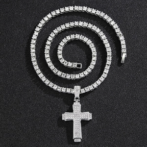 Détail d'un pendentif croix hip-hop argenté serti de strass sur une chaîne de tennis