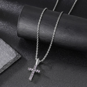 Detail shot of a silver cross pendant with purple zircon stones on a rope chain