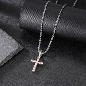 Detailed shot of hip hop cross pendant with pink cubic zirconia on a silver rope chain