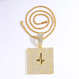 Détail d'un pendentif carré doré avec strass sertis et ligne ECG noire sur chaîne torsadée