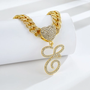 Détail de la chaîne cubaine dorée avec fermoir coeur et pendentif lettre E serti