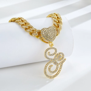 Vue détaillée d'un collier chaîne cubaine dorée avec un pendentif lettre E pavé de strass