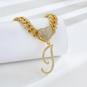 Détail de la chaîne cubaine dorée avec fermoir coeur et pendentif lettre J serti de strass