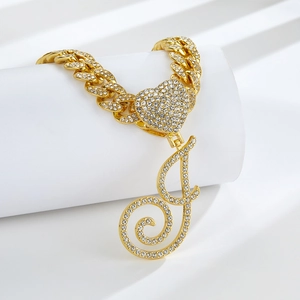 Détail d'une chaîne cubaine dorée avec pendentif cœur et lettre J sertie de strass brillants