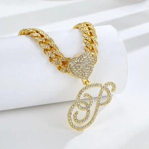 Gros plan d'une chaîne cubaine dorée avec un cœur serti de strass et un pendentif lettre P