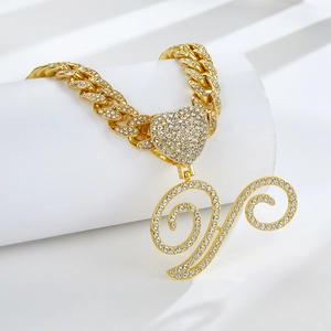 Vue détaillée du collier gourmette dorée avec pendentifs cœur et lettre sertis