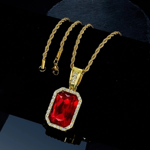 Macro shot of rectangular red gemstone pendant with white diamonds on gold rope chain