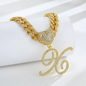 Détail du collier à maillons cubains dorés avec cœur serti et grand pendentif lettre H