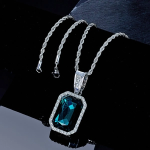 Macro detail of emerald-cut green gemstone pendant with white diamond accents on rope chain