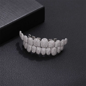 Close-up of hip hop silver grillz with sparkling diamonds on black leather surface