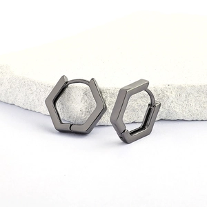 Boucles d'oreilles huggies hexagonales en métal poli sur fond de pierre décoratif