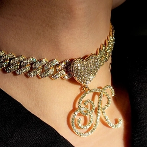 Détail de la chaîne cubaine dorée avec lien en cœur et grand pendentif lettre R serti