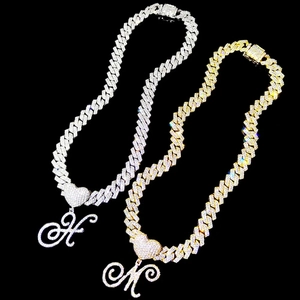 Détail de colliers cubains sertis de zircons avec pendentifs lettres et cœur poli