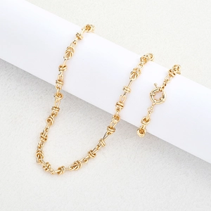 Collier doré à maillons noués avec fermoir à ressort sur présentoir blanc moderne