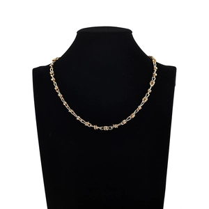 Collier en métal doré style barbelé noué exposé sur un mannequin de cou noir