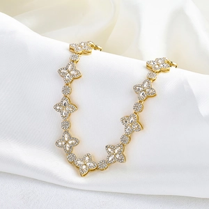 Close-up of gold clover necklace with sparkling zircon pavé on white satin background
