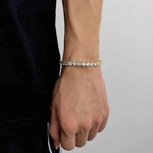 Gros plan d'un bracelet de tennis en or 4mm avec zircons ronds portés sur un poignet d'homme