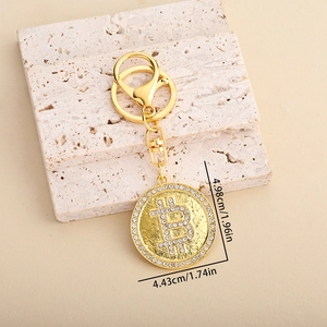 Portachiavi Bitcoin dorato con strass brillanti appoggiato su pietre decorate