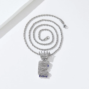 Macro shot of silver hip-hop letter E pendant with crown and blue water drop details