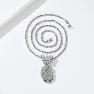 Macro detail of iced-out silver crown letter G pendant with purple teardrop on rope chain