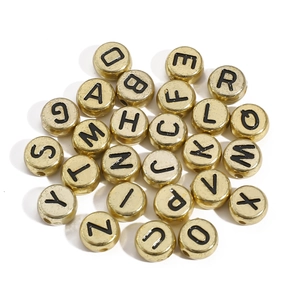 Detailed view of round golden acrylic alphabet beads with black letters for DIY jewelry