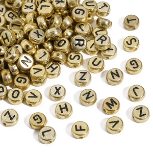 Macro shot of gold acrylic letter beads with black A-Z engraving for DIY jewelry crafting