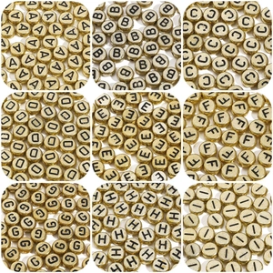 Macro display of golden acrylic alphabet beads with black letters for DIY jewelry making