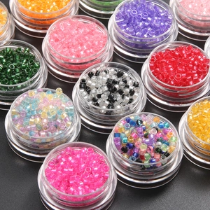 Macro view of assorted colorful 2mm glass seed beads in transparent storage containers