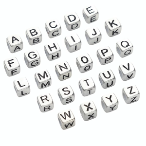 Macro shot of silver acrylic cube beads with A-Z black engraved letters for DIY jewelry
