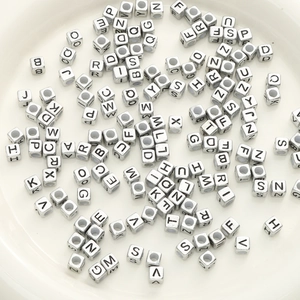 Square silver acrylic alphabet beads for DIY jewelry making in a white ceramic dish