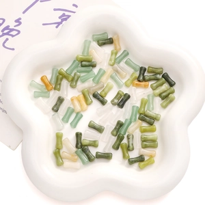 Gros plan de perles de pierre multicolores polies en forme de bambou dans un plat
