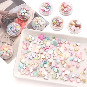 Pastel DIY shell bead set with stars and hearts in clear storage jars on a white tray