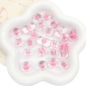Vue macro de diverses perles en acrylique rose de formes variées sur un plateau blanc