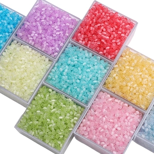 Close-up of 4mm jelly cat-eye glass beads in various colors stored in an organizer box